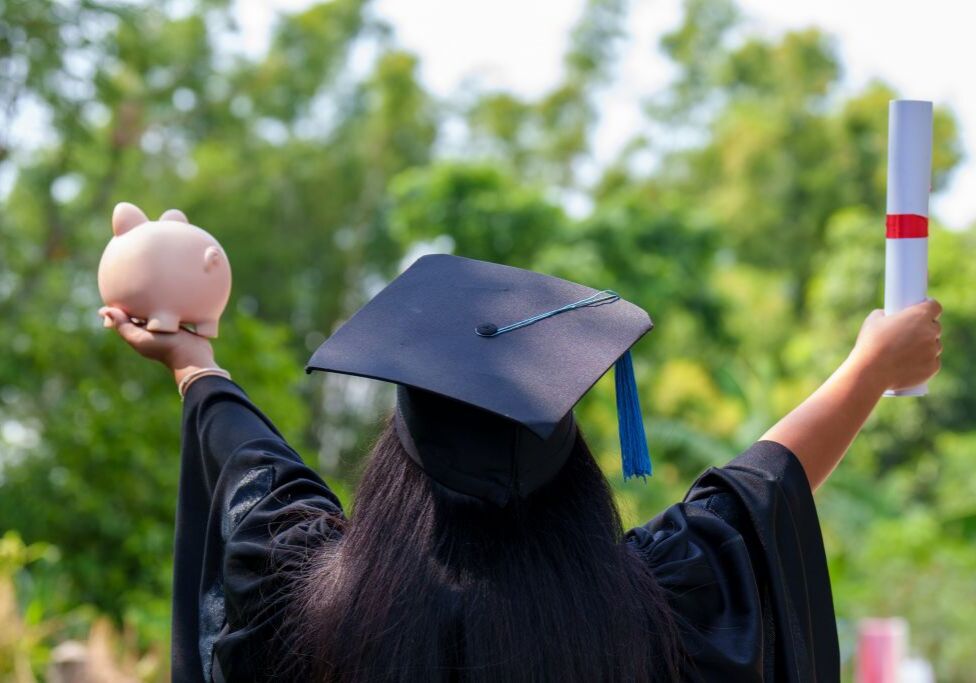 Graduate with diploma and piggy bank